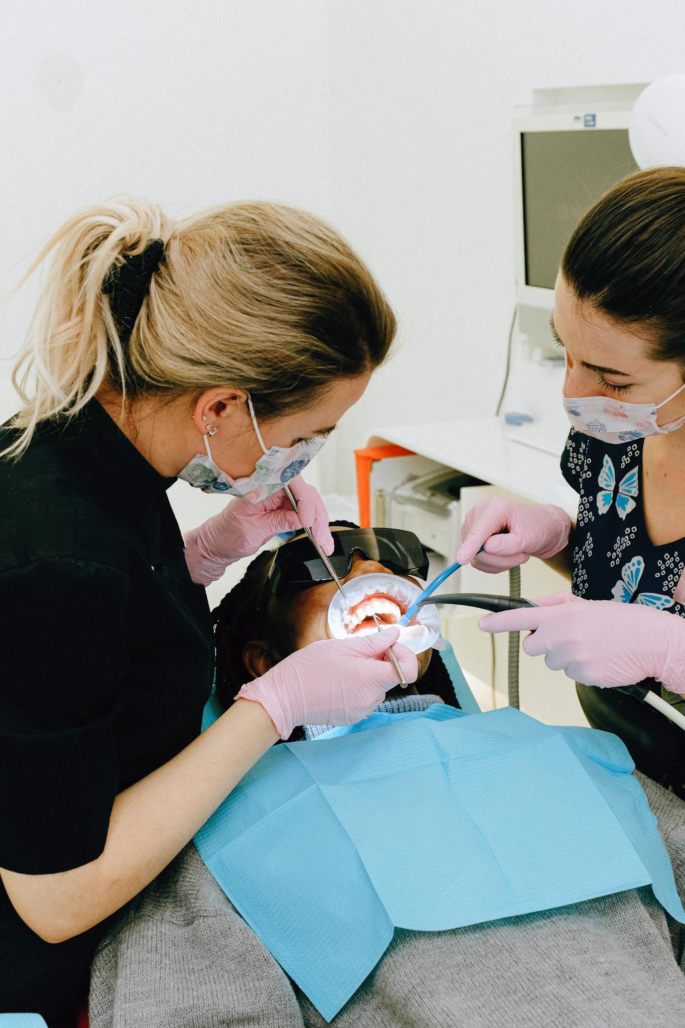 Dentists working on a patient with tools in a modern clinic setting.